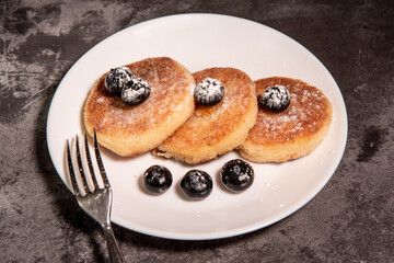 Cheesecakes (curd pancakes) with blueberries on a white plate. Healthy tasty breakfast. Close-up