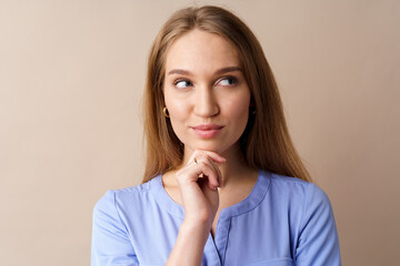 Pensive young businesswoman thinking about some idea against beige background