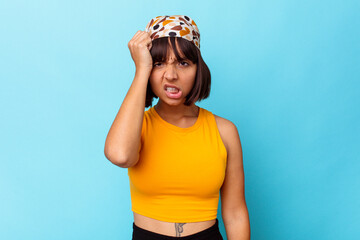 Young mixed race woman isolated on blue background forgetting something, slapping forehead with palm and closing eyes.