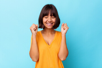 Naklejka na ściany i meble Young mixed race woman isolated on blue background celebrating a victory, passion and enthusiasm, happy expression.