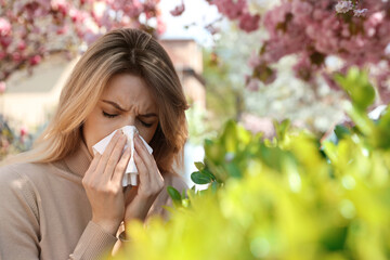 Woman suffering from seasonal pollen allergy outdoors - obrazy, fototapety, plakaty