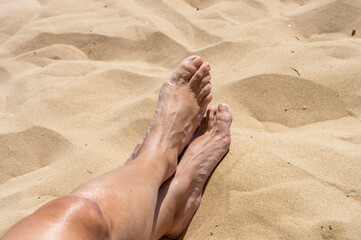 Woman feet crossed on the sandy beach, Guardamar of the Segura, Spain