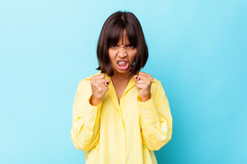 Young mixed race woman isolated on blue background upset screaming with tense hands.