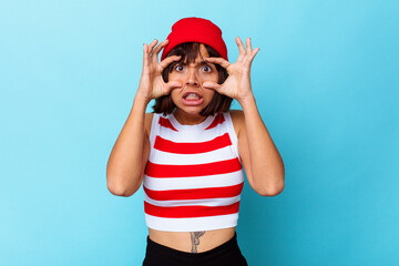 Young mixed race woman isolated on blue background keeping eyes opened to find a success opportunity.