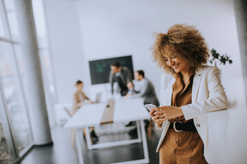 Smiling businesswoman using mobile phone in modern office