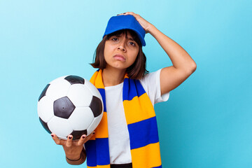 Young mixed race woman watching soccer isolated on blue background being shocked, she has...