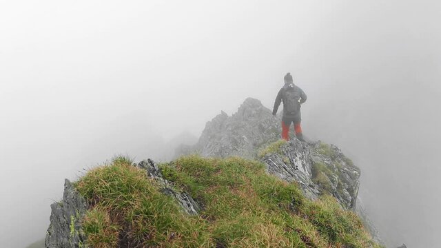 Amazing landscape with a hiker walking on mountain cliffs in a foggy day