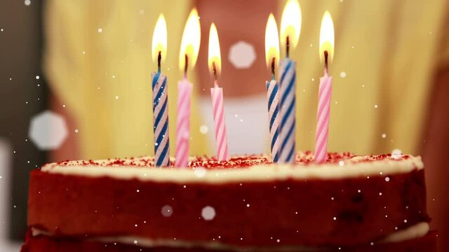 Animation of white spots of light moving over lit candles on birthday cake