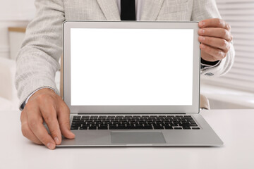 Businessman with modern laptop at white table indoors, closeup. Space for design