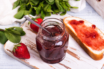 Jar of strawberry jam and slices of bread