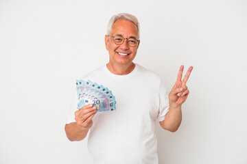 Senior american man holding bill isolated on white background joyful and carefree showing a peace symbol with fingers.