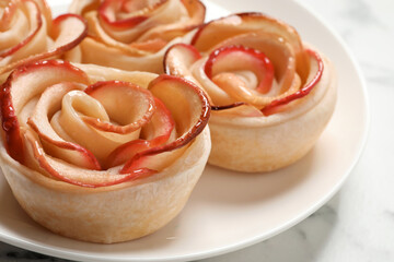 Obraz na płótnie Canvas Freshly baked apple roses on white table, closeup. Beautiful dessert