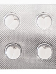 Heart-shaped white pills in blister package, close-up