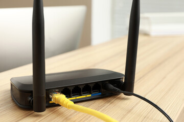 Modern wi-fi router on wooden counter indoors, closeup