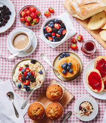 BIG BREAKFAST with blueberry pancake, bread, coffee, muffin, yoghurt, fruits ON A RED SQUATE TABLECLOTH