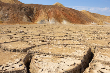 A dry, lifeless, barren clay land cracked in the African desert during global warming and climate...