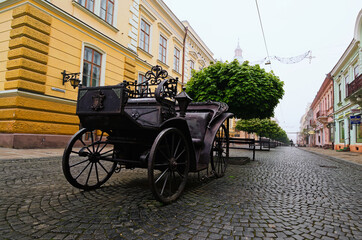 Fototapeta premium Chernivtsi, Ukraine-May 14, 2021:Scenic foggy morning landscape view of famous pedestrian Olga Kobylianska street. Iron coach is famous travel destination in the city. Travel and tourism concept