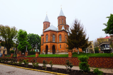 Fototapeta na wymiar Chernivtsi, Ukraine-May 14, 2021:Scenic foggy landscape view of the street in the downtown. Ancient red brick The Armenian Church of the Holy Apostles Peter and Paul. Christian Orthodox cathedral