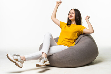 Portrait of cheerful woman with laptop sitting in beanbag isolated on white background