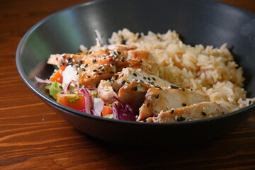 Curry indian food - bowl of stir spicy rice with chicken and vegetables on wooden table