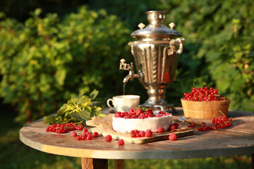 Summer atmosphere. Russian cuisine. Dacha, nature. Cottage cheese pie, cake with fresh berries: red currants and raspberries on an old wooden table. Samovar with a cup. Background image, copy space