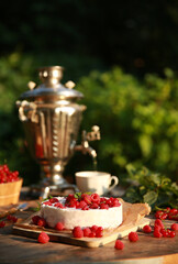 Summer atmosphere. Russian cuisine. Dacha, nature. Cottage cheese pie, cake with fresh berries: red currants and raspberries on an old wooden table. Samovar with a cup. Background image, copy space