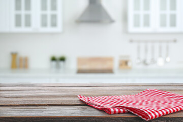 Red checkered napkin on wooden table and blurred view of stylish kitchen interior. Space for design