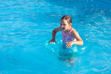 the girl holds on to a transparent blue inflatable circle with her hands, has a good time on vacation in a hotel on a sunny day. 