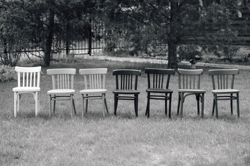 a black and white frame from a retro movie, a row of wooden Viennese chairs on the lawn in the backyard garden, a retro wedding ceremony. 
