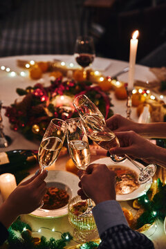 Cheers with champagne. People clink glasses of champagne at the holiday table on New Year's Eve. High quality photo