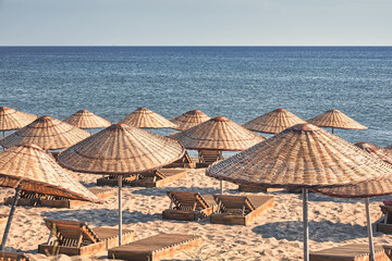 an empty beach in island with  beach umbrellas, sun loungers and a clear sky