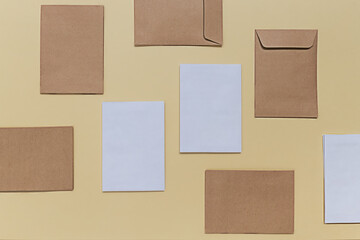 Fototapeta premium Back to school creative concept. Blank mock up with white and beige envelopes on a yellow paper background. Minimalist flat lay, top view composition.