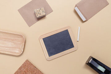 Fototapeta premium Back to school creative concept. Blank mock up with a chalk board, envelopes and notebook on a yellow paper background. Minimalist flat lay, top view.