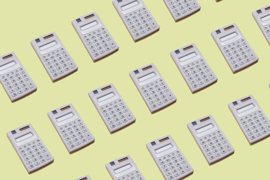 Back to school creative concept. Small white digital calculator pattern on a yellow paper background.
