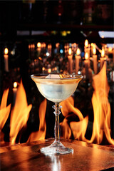 Yellow cocktail in a beautiful glass on copper plates against the background on the real fire. close up. High quality photo