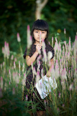 Cute little girl enjoying bloom of wild flowers in the field of meadow