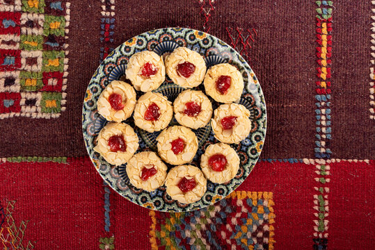 Traditional Moroccan handmade cookies in a ceramic plate on a colorful carpet.