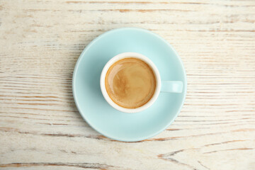Cup of tasty coffee on white wooden table, top view