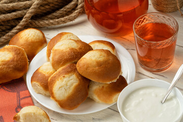 Cottage cheese pastry pies, vatrushka in Russian cuisine Pitcher and glass of compote bowl of sour cream or yogurt on wooden background