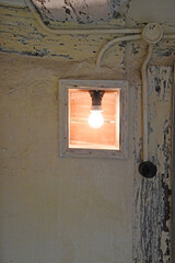 Glühbirne in stehender Fassung in altem Haus in einer Nische 