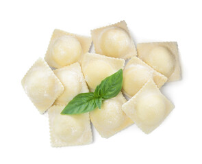 Uncooked ravioli and basil on white background, top view