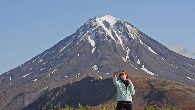 Hiking and eco tourism woman makes selfie against mountain