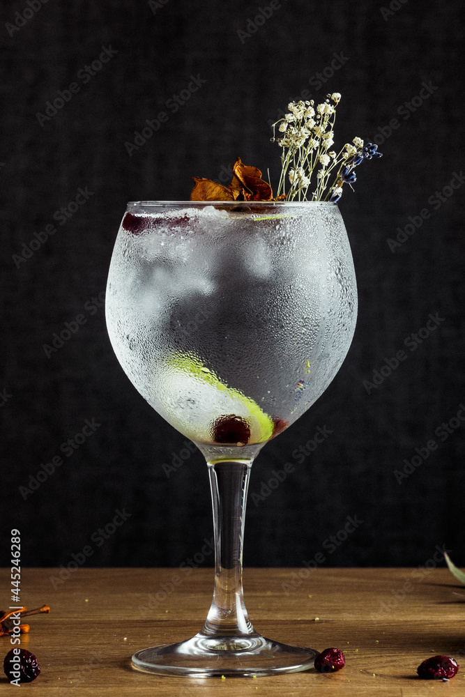 Sticker Vertical shot of freshly prepared and decorated gin and tonic on a wooden table