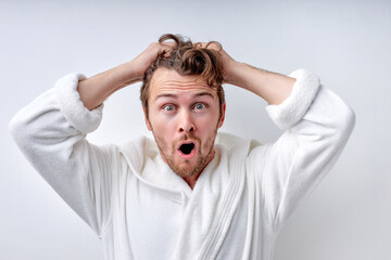 Unbelievable news. Portrait of emotional guy in bathrobe opening mouth and eyes in shock, looking at camera on white studio background. Amazed caucasian man feeling astonished. Human emotions