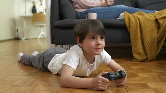 boy laying on floor playing video games at home	