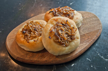 Tasty onion roll on wooden plate