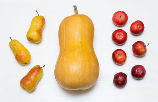 Large yellow pumpkin, apples and pears on a white wooden table. Autumn harvest.