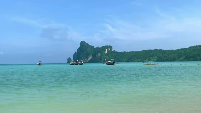koh phi phi bech in krabi, thailand. turquoise water, boats in lagoon, jungle green rock mountain