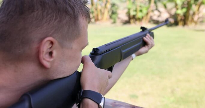 Young man shoots rifle in street shooting range 4k movie