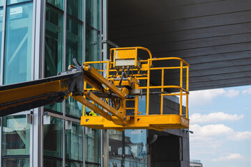 Metal basket for lifting people on the boom of the crane. Yellow. glass. bridge.
